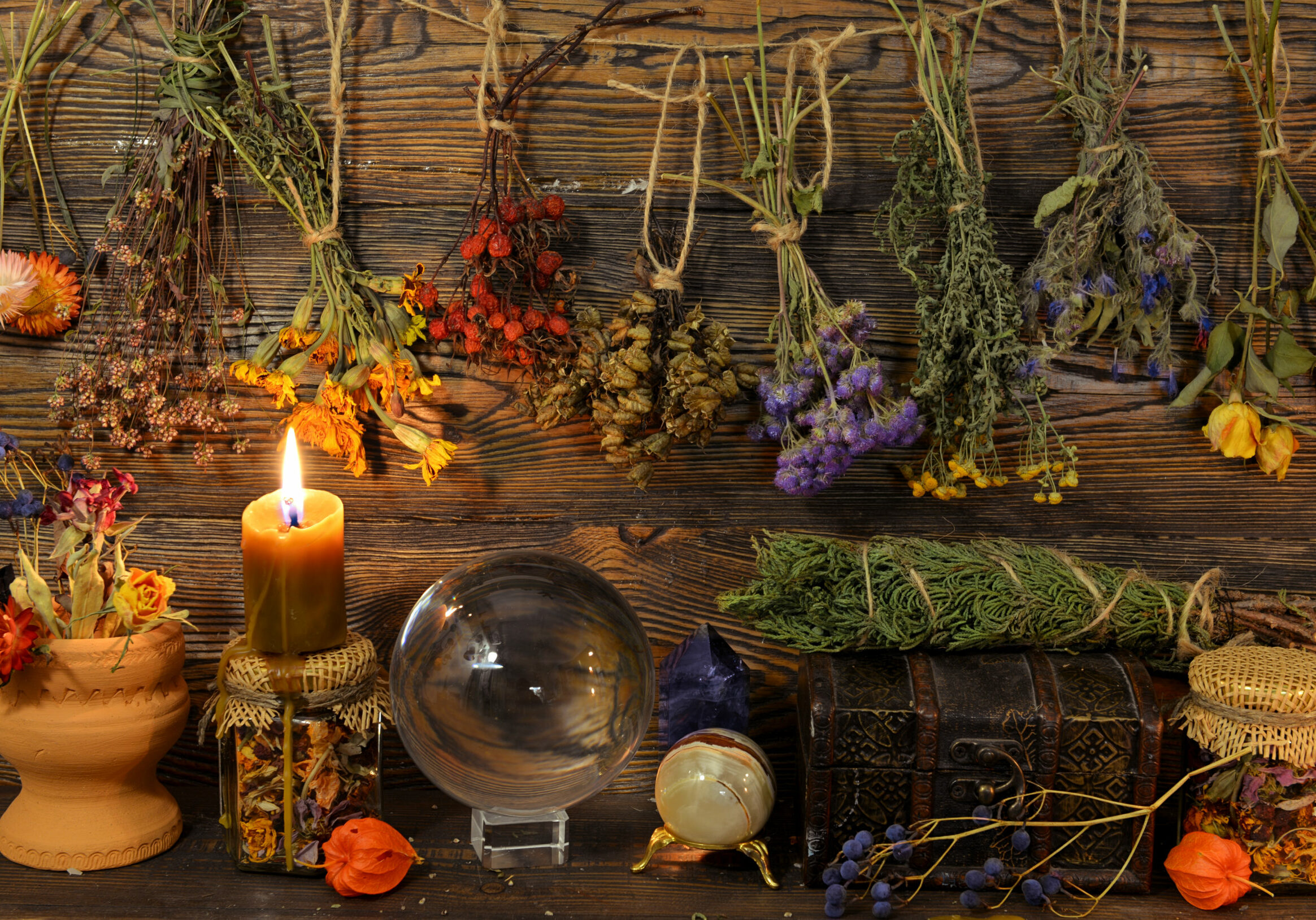 Still life with dry herbs, crystal ball, bottle and burning candle on witch table. Esoteric, wicca and occult background, fortune telling and divination ritual, mystic concept